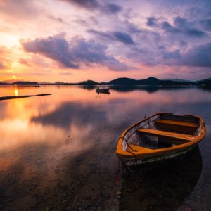 Wandbild - Sonnenuntergang am See mit Holzboot